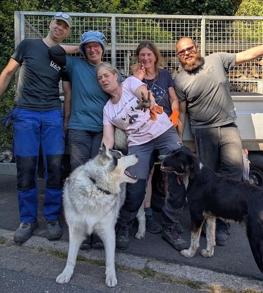 Fünf Helfende und ein Hund vor einem Anhänger nach einem Einsatz